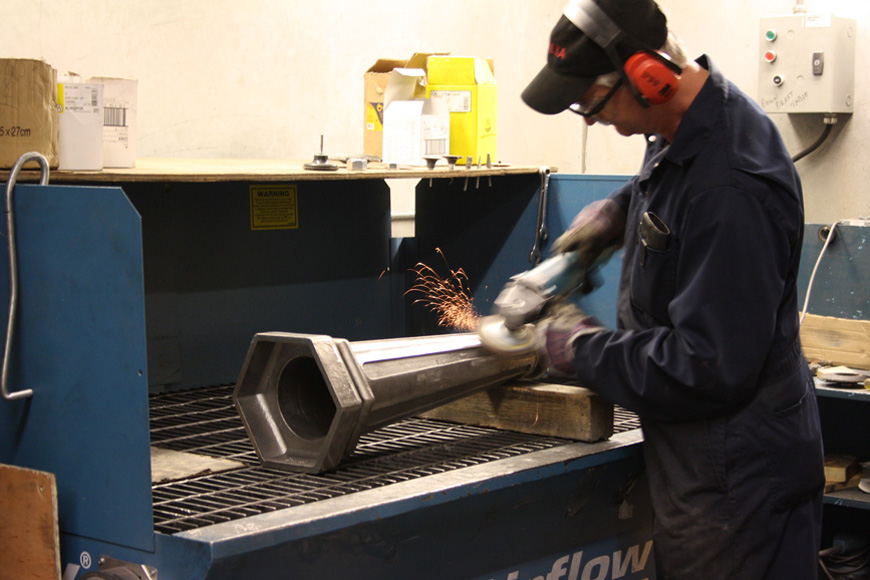 Sparks fly from a grinder wheel as a steel surface is machined smooth