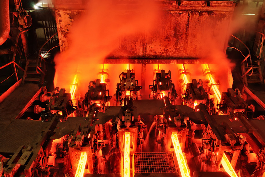 Glowing bars of steel are extruded from a continuous metal casting machine