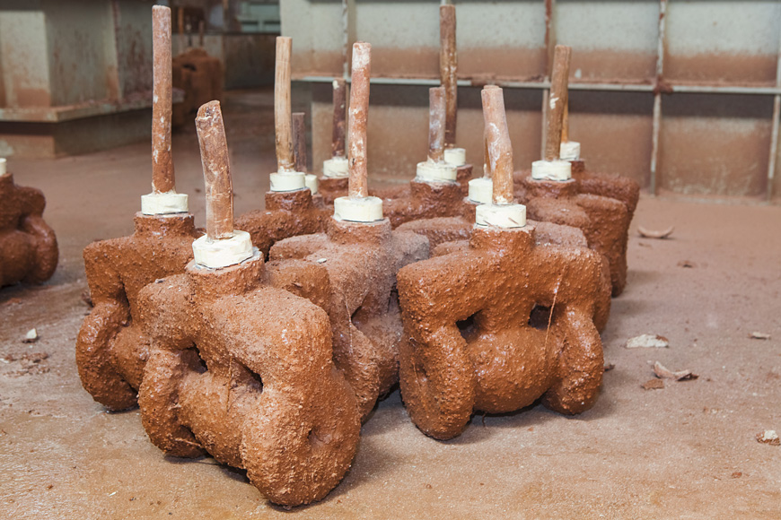 A group of similar sandy-looking blobs are molds made of aggregate shells around wax patterns 