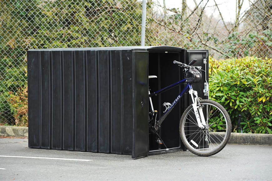 A blue Kona bicycle peeks a wheel out of a bike locker