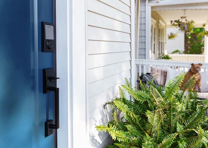 Schlage Sense matte black smart lock on blue front door.